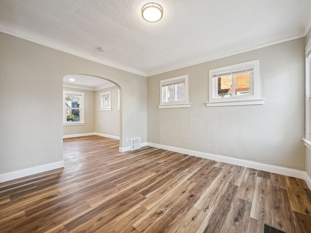 spare room featuring hardwood / wood-style flooring, a healthy amount of sunlight, crown molding, and a textured ceiling