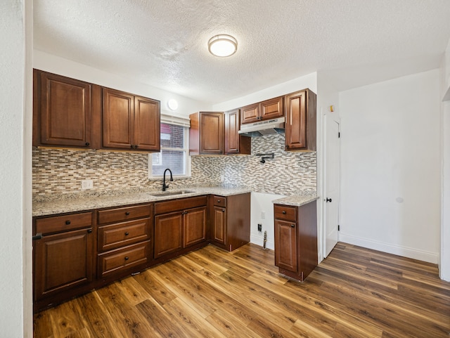 kitchen featuring dark wood-type flooring, sink, light stone countertops, a textured ceiling, and tasteful backsplash