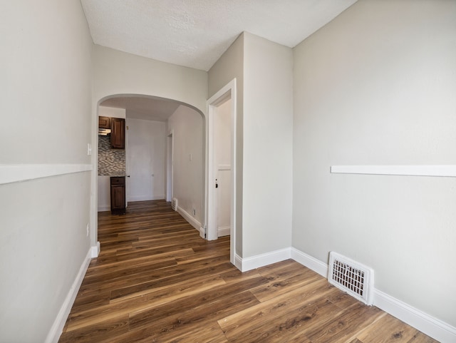 hallway with a textured ceiling and dark wood-type flooring