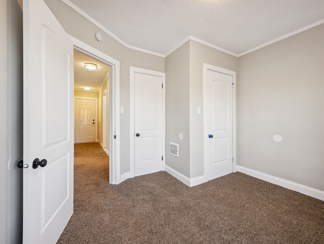 unfurnished bedroom featuring a textured ceiling, dark carpet, a closet, and crown molding