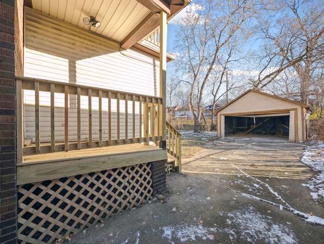 snow covered deck with a garage and an outdoor structure