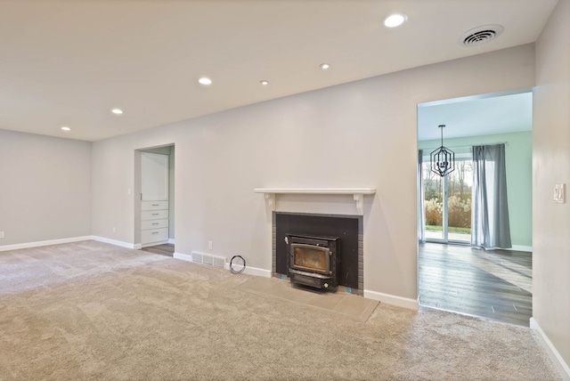 unfurnished living room featuring carpet and a wood stove