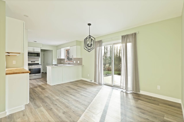 kitchen featuring kitchen peninsula, backsplash, stainless steel appliances, light hardwood / wood-style flooring, and white cabinetry