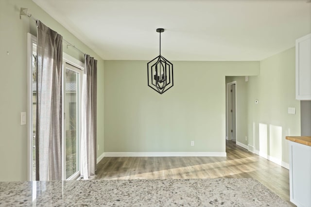 unfurnished dining area featuring a notable chandelier and light wood-type flooring