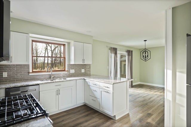 kitchen with dark wood-type flooring, sink, stainless steel dishwasher, white cabinetry, and kitchen peninsula