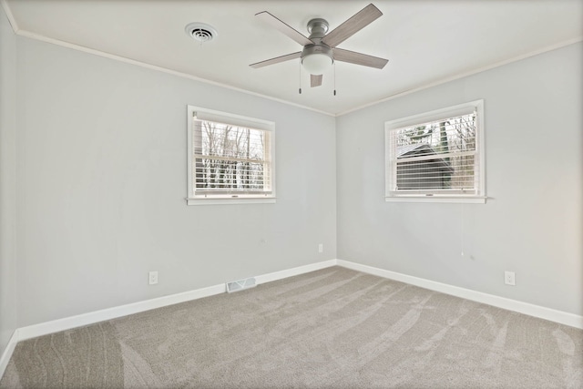 carpeted spare room with ceiling fan, a healthy amount of sunlight, and ornamental molding