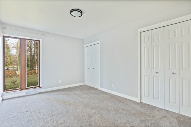 unfurnished bedroom with light carpet and two closets