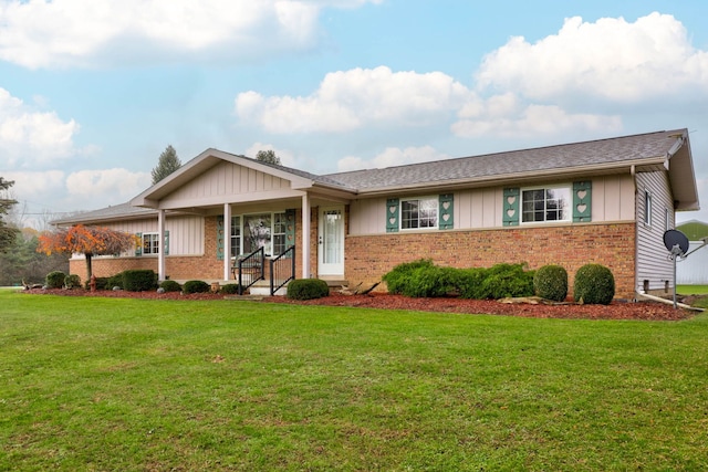 single story home featuring board and batten siding, a front yard, and brick siding