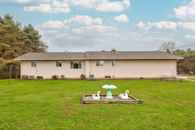 rear view of property with central AC and a lawn