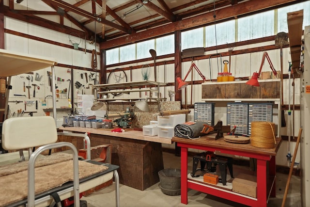 misc room featuring lofted ceiling, concrete flooring, and a workshop area