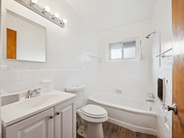 full bathroom featuring tiled shower / bath combo, hardwood / wood-style floors, toilet, vanity, and tile walls