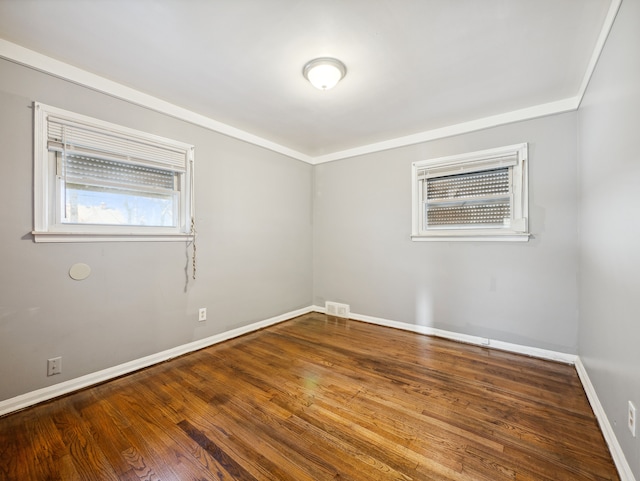 spare room featuring wood-type flooring and ornamental molding