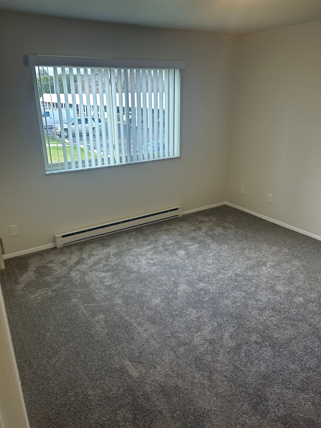 spare room featuring dark carpet and a baseboard heating unit