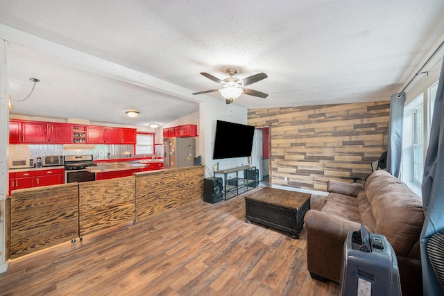 living room with sink, vaulted ceiling, a textured ceiling, dark hardwood / wood-style floors, and ceiling fan