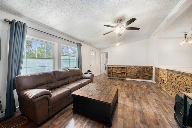 living room with dark wood-type flooring, vaulted ceiling, a textured ceiling, and ceiling fan with notable chandelier