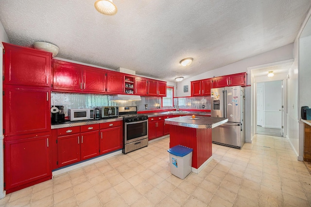 kitchen featuring lofted ceiling, sink, stainless steel appliances, a center island, and tasteful backsplash