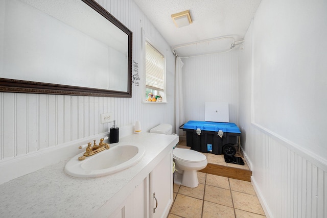 bathroom featuring vanity, toilet, tile patterned flooring, and a textured ceiling