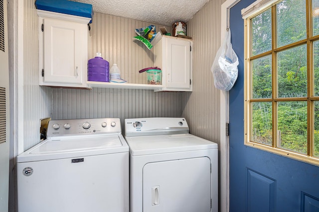 clothes washing area featuring cabinets, a textured ceiling, and washer and clothes dryer