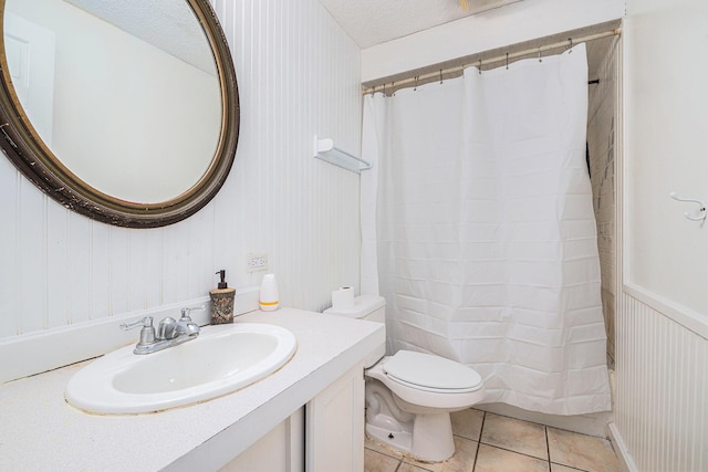 bathroom with walk in shower, toilet, a textured ceiling, vanity, and tile patterned flooring