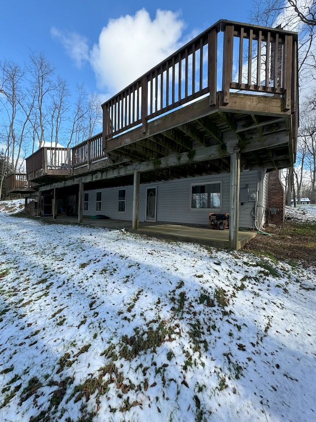 snow covered rear of property featuring a wooden deck