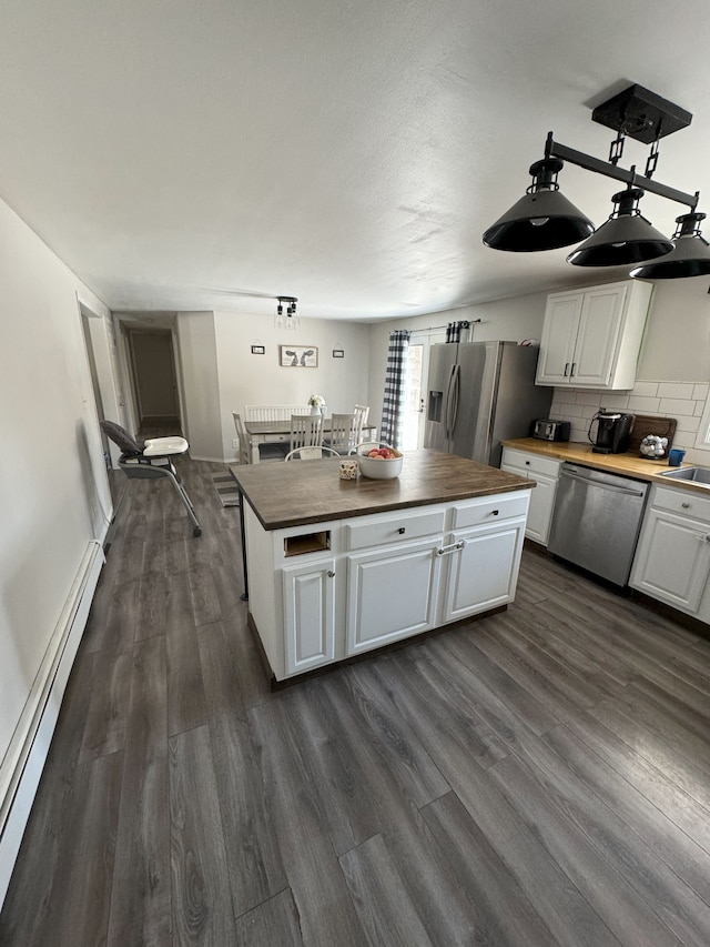 kitchen with wooden counters, stainless steel appliances, white cabinetry, and a baseboard radiator