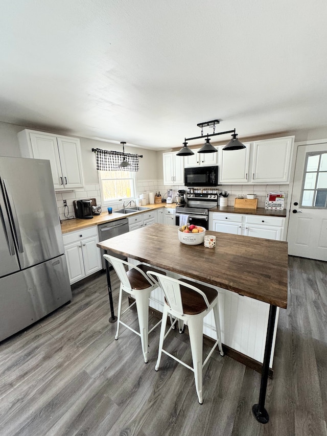 kitchen featuring wooden counters, dark hardwood / wood-style flooring, backsplash, stainless steel appliances, and white cabinets