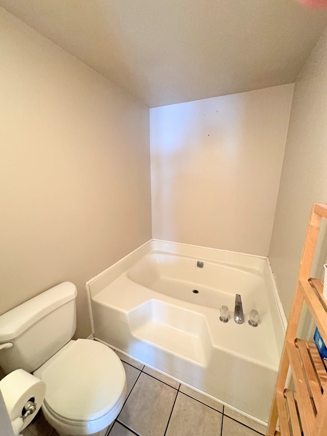 bathroom featuring toilet, a washtub, and tile patterned flooring