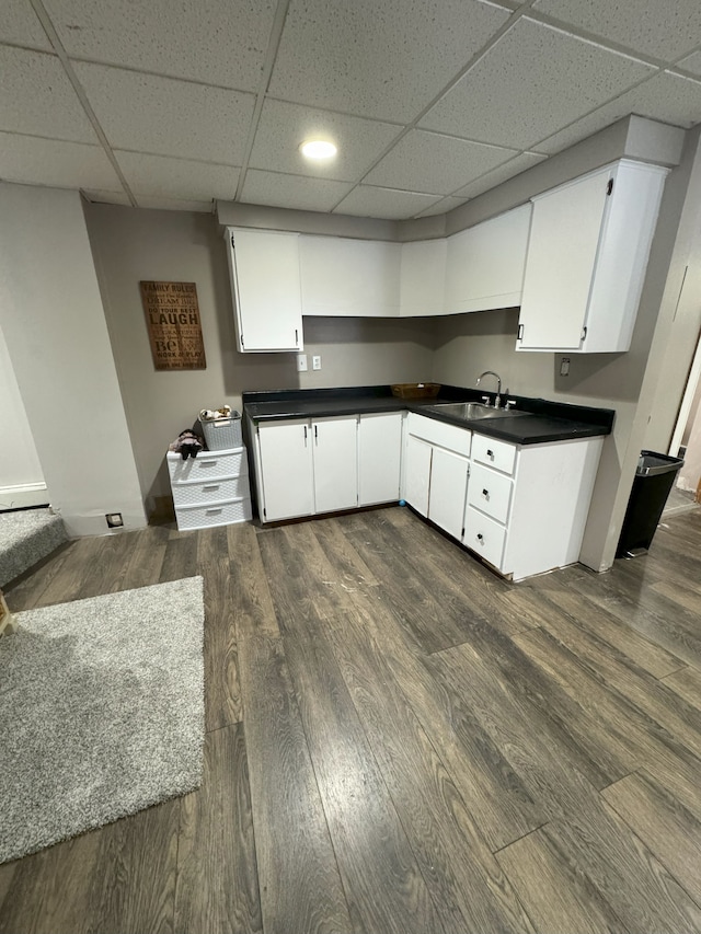 kitchen with dark hardwood / wood-style flooring, white cabinetry, a paneled ceiling, and sink