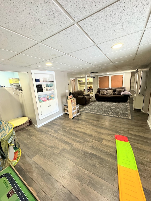 game room featuring dark hardwood / wood-style floors and a drop ceiling