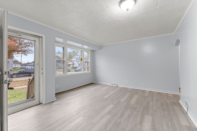 spare room with ornamental molding, a wealth of natural light, and light hardwood / wood-style flooring