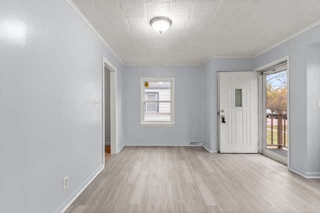 empty room with crown molding, plenty of natural light, and light hardwood / wood-style floors