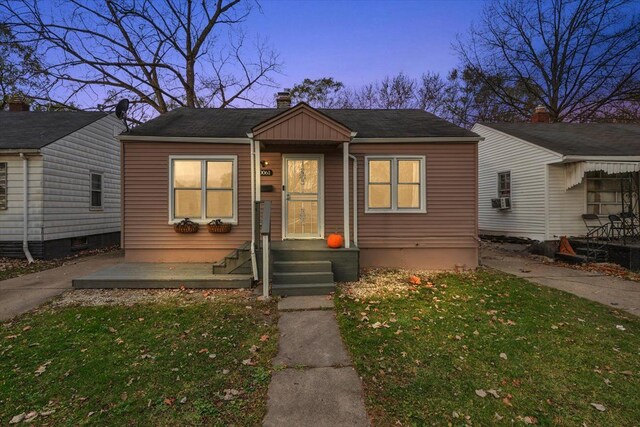 bungalow featuring cooling unit and a lawn