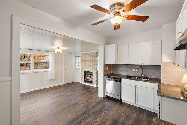 kitchen featuring stainless steel dishwasher, dark hardwood / wood-style floors, white cabinetry, and a fireplace