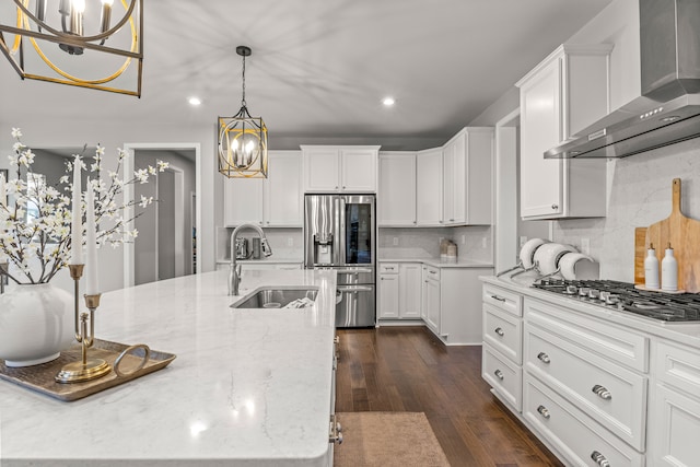 kitchen with white cabinets, wall chimney range hood, sink, appliances with stainless steel finishes, and dark hardwood / wood-style flooring