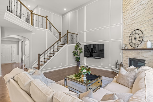 living room featuring hardwood / wood-style floors, a towering ceiling, and a fireplace