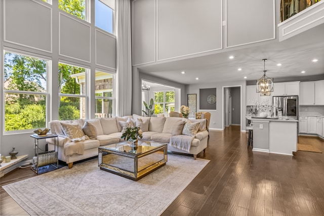 living room with a chandelier, a high ceiling, and dark hardwood / wood-style flooring