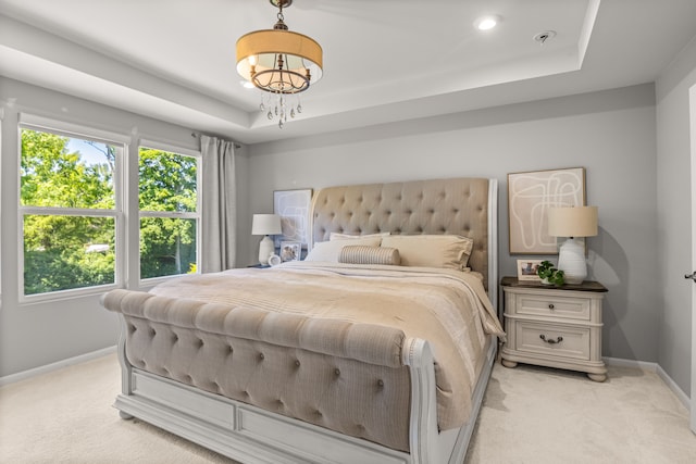 bedroom with light carpet and a tray ceiling