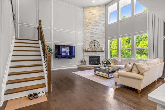 living room featuring dark hardwood / wood-style floors, a towering ceiling, and a fireplace