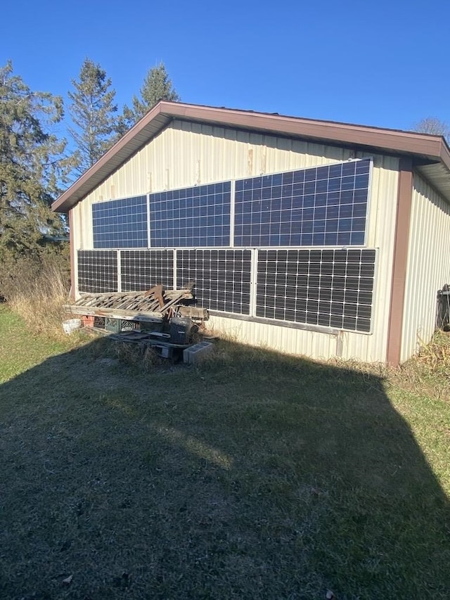 view of side of home with solar panels and a lawn