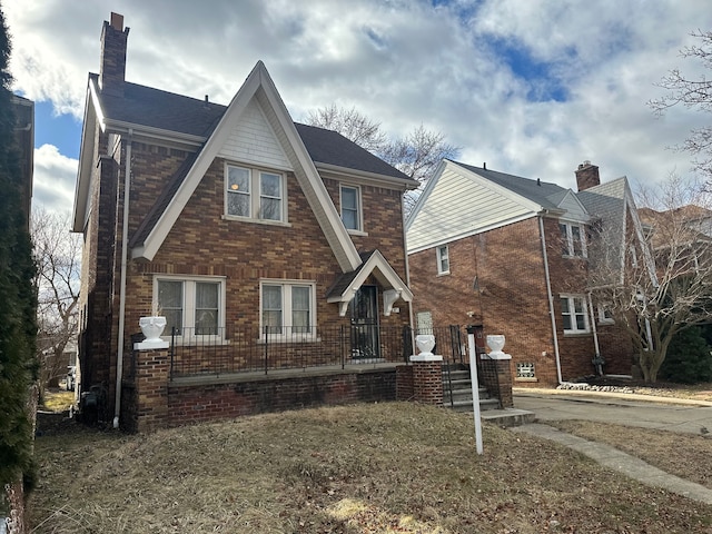 tudor home with brick siding and a chimney