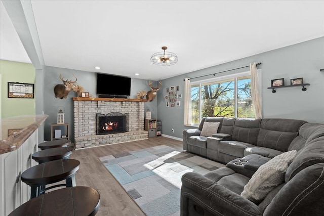 living room with a brick fireplace and light hardwood / wood-style flooring