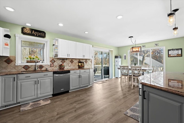 kitchen with white cabinetry, sink, stainless steel dishwasher, dark hardwood / wood-style floors, and decorative light fixtures