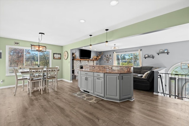 kitchen with decorative light fixtures, gray cabinets, an inviting chandelier, and dark hardwood / wood-style floors