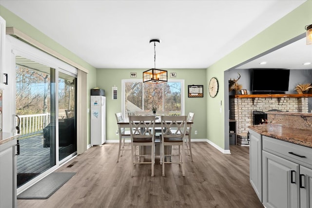 dining space with hardwood / wood-style floors and a brick fireplace