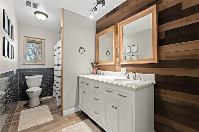 bathroom featuring hardwood / wood-style floors, vanity, toilet, and tile walls