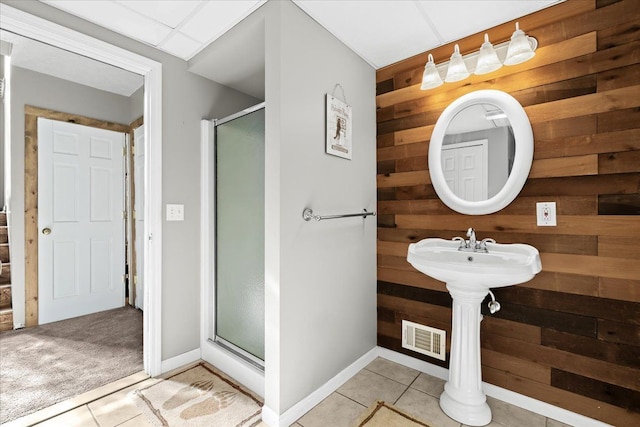 bathroom with tile patterned flooring, wood walls, and an enclosed shower