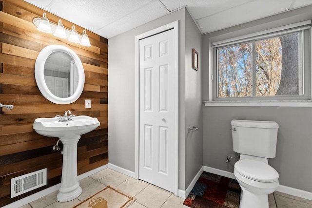 bathroom featuring tile patterned floors, toilet, and wooden walls