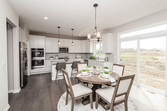 dining space with dark hardwood / wood-style flooring, sink, and an inviting chandelier