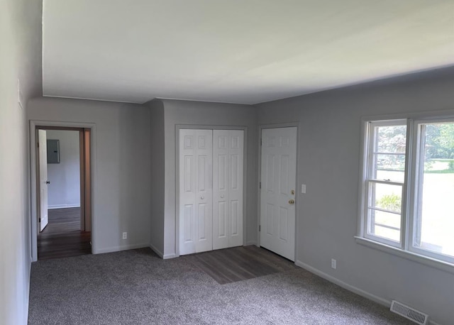 unfurnished bedroom featuring electric panel, a closet, and dark carpet