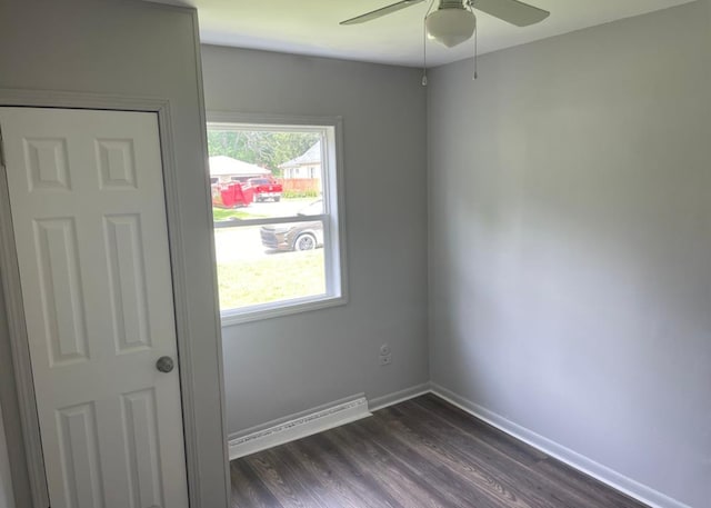 empty room with dark hardwood / wood-style floors, a baseboard radiator, and ceiling fan